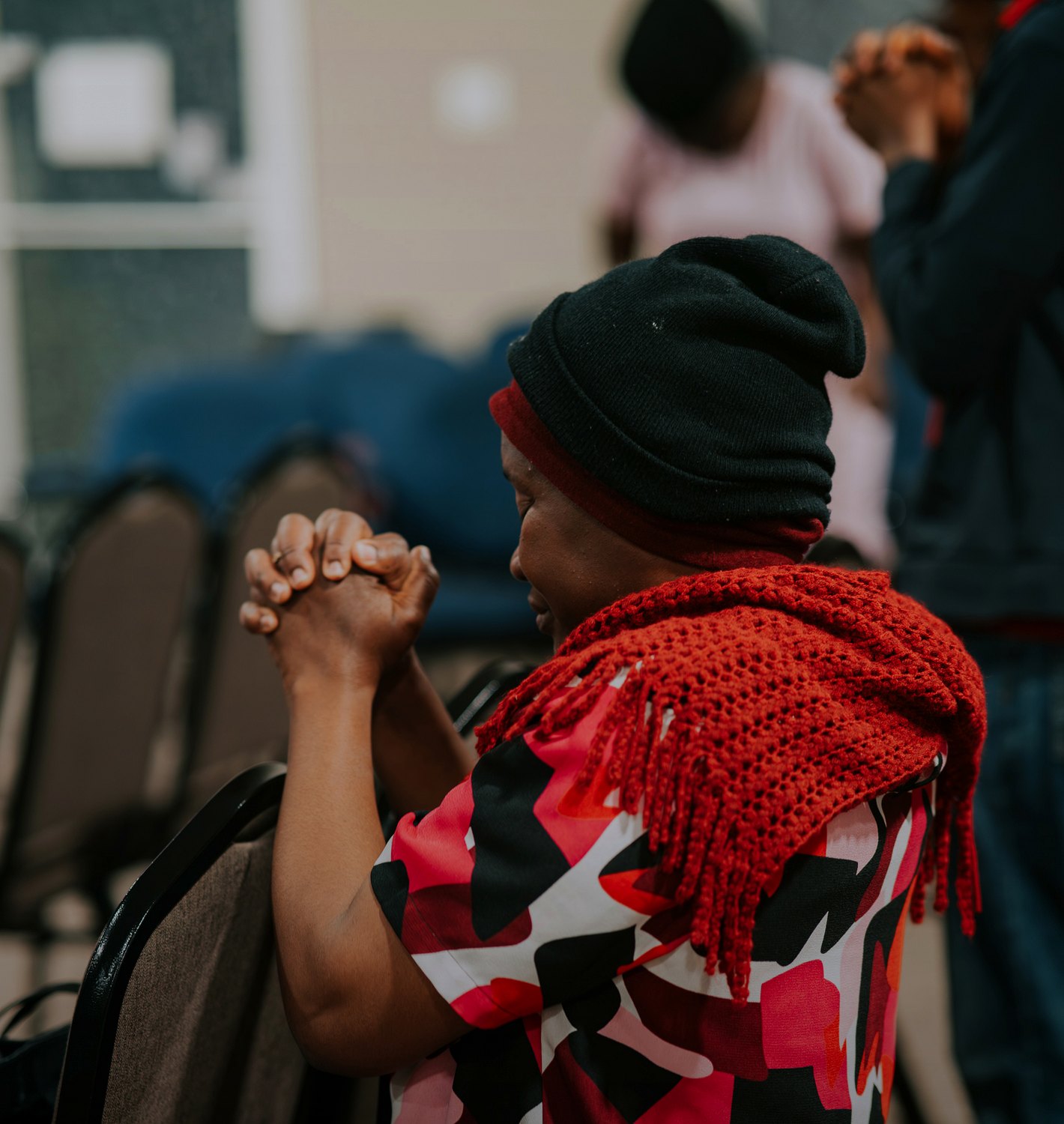 A seated church member praying with clasped hands