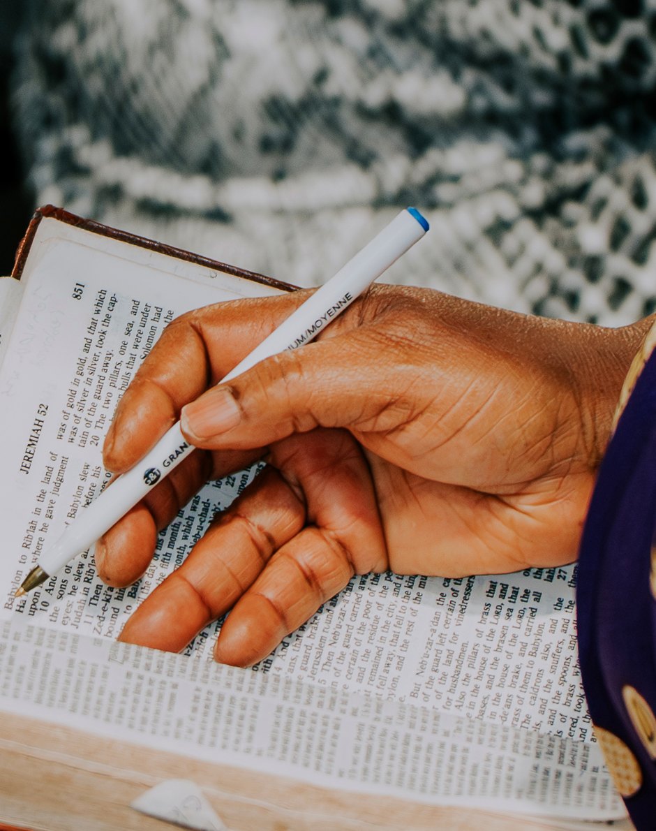 A hand writing notes in an open Bible